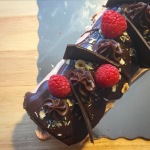 Chocolate Swiss Roll with raspberries and toasted hazelnuts on top.