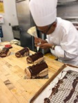Chef is piping rosettes with the chocolate glaze.